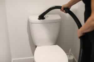 Go_Clean-October_6th-Web_Ready-86 - House Work Person using a vacuum to clean the toilet tank in a bathroom.