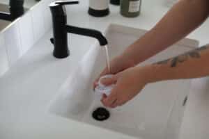 Go_Clean-Sept.22-Web_Ready-125-1 - House Work Person at a sink washing hands, getting ready to clean bathroom sinks and countertops.