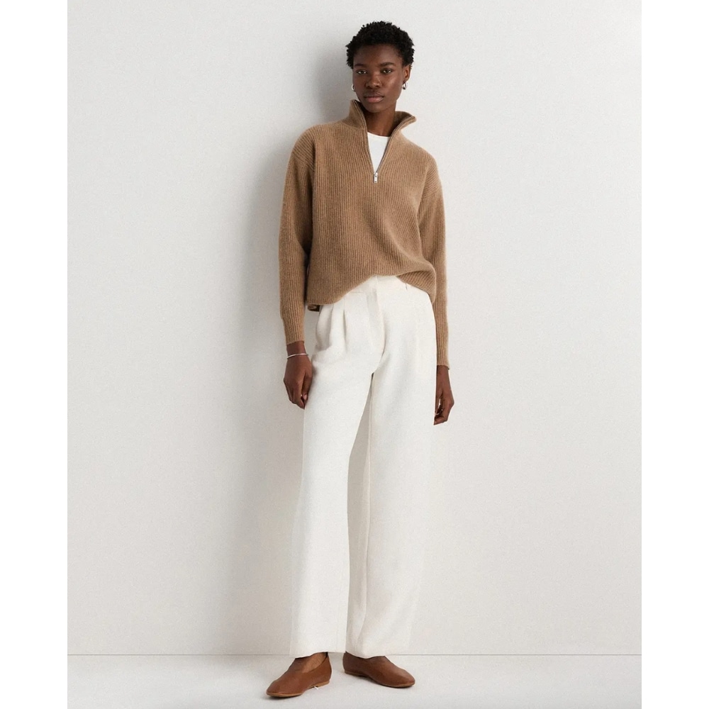 Model wearing a tan ribbed half-zip sweater tucked into white wide-leg trousers with brown loafers.