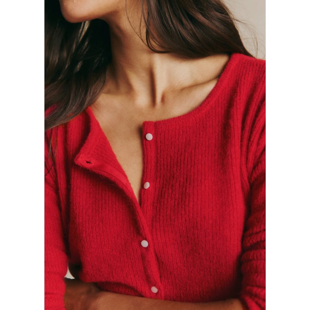 Close-up of a woman wearing a red button-front knit cardigan, focusing on the neckline and shoulders.