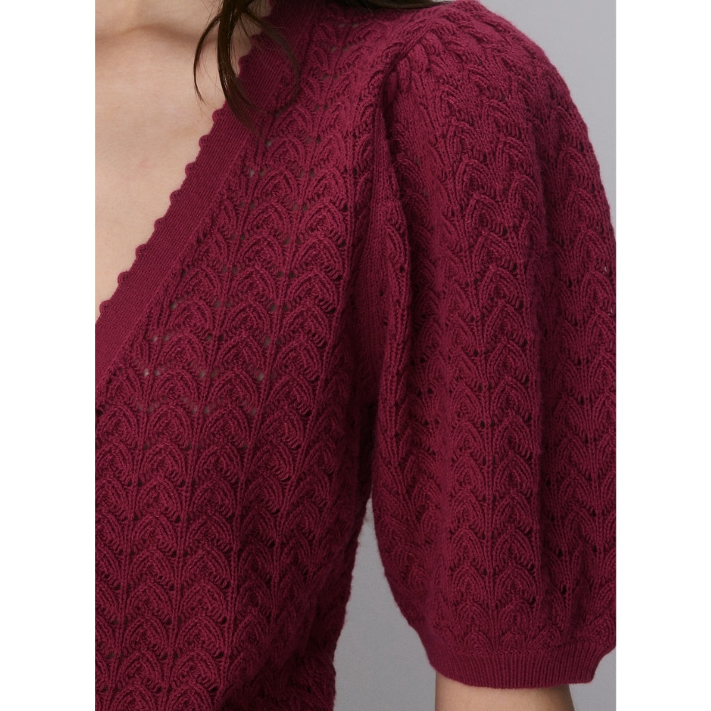 Close-up of a burgundy knit cardigan with a scalloped V-neck and voluminous short puff sleeve detail (fabric texture shown).