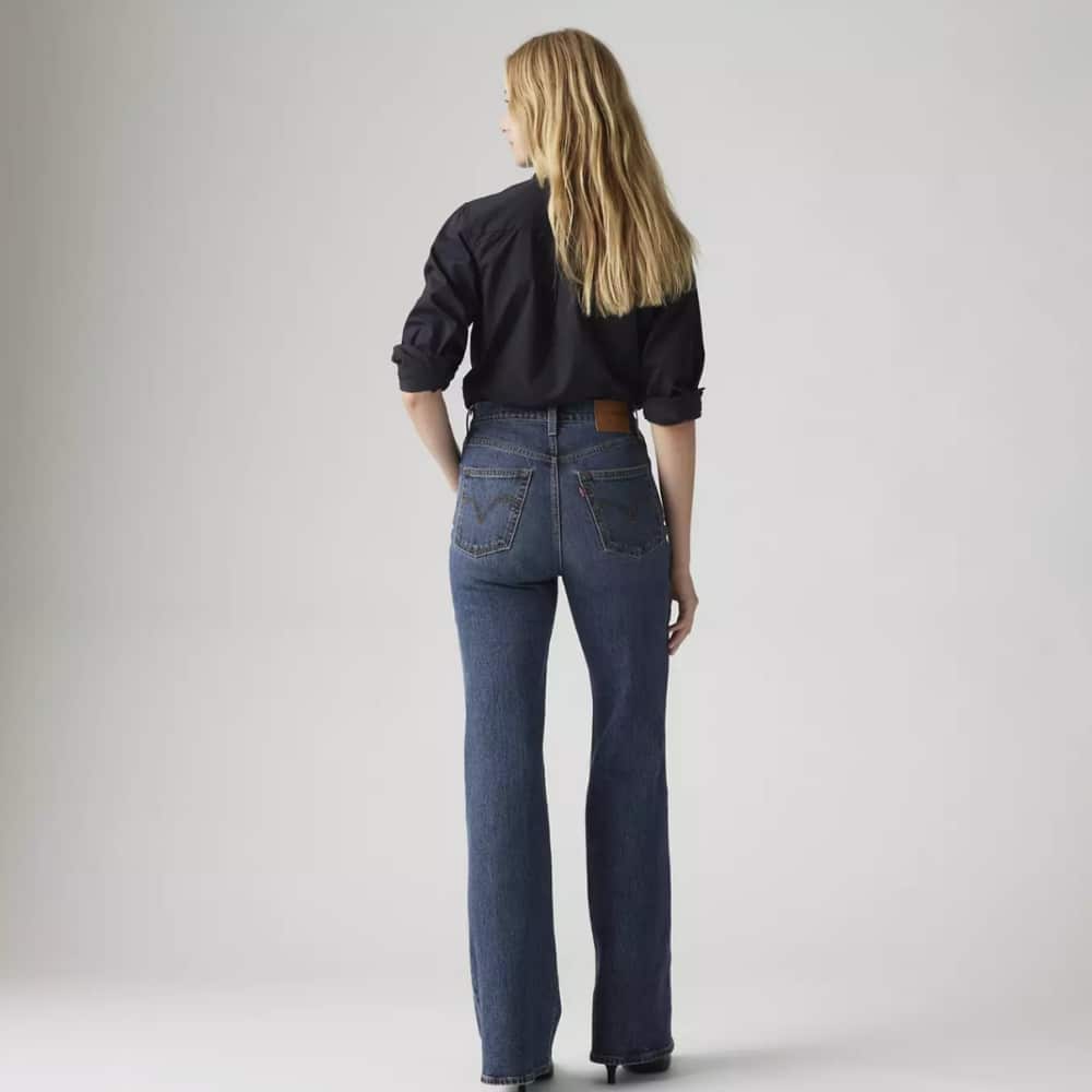 Back view of a person wearing a black shirt and high-waisted blue jeans with a brown belt.