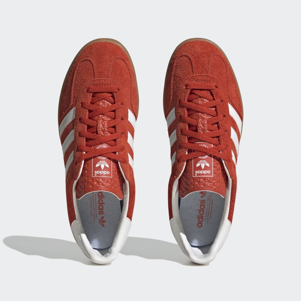 Top-down view of red Adidas sneakers with white stripes and laces visible on each shoe