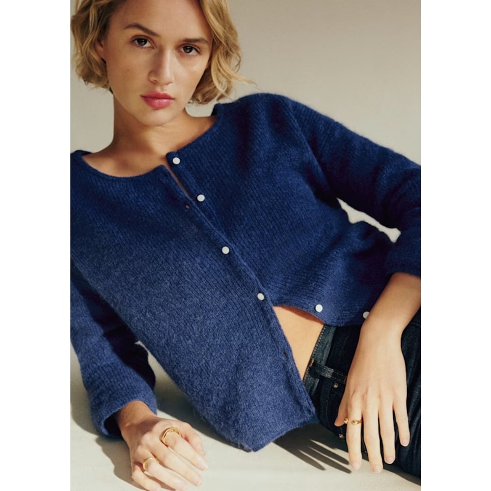 Woman modeling a navy blue knit cardigan with silver buttons, posing casually.