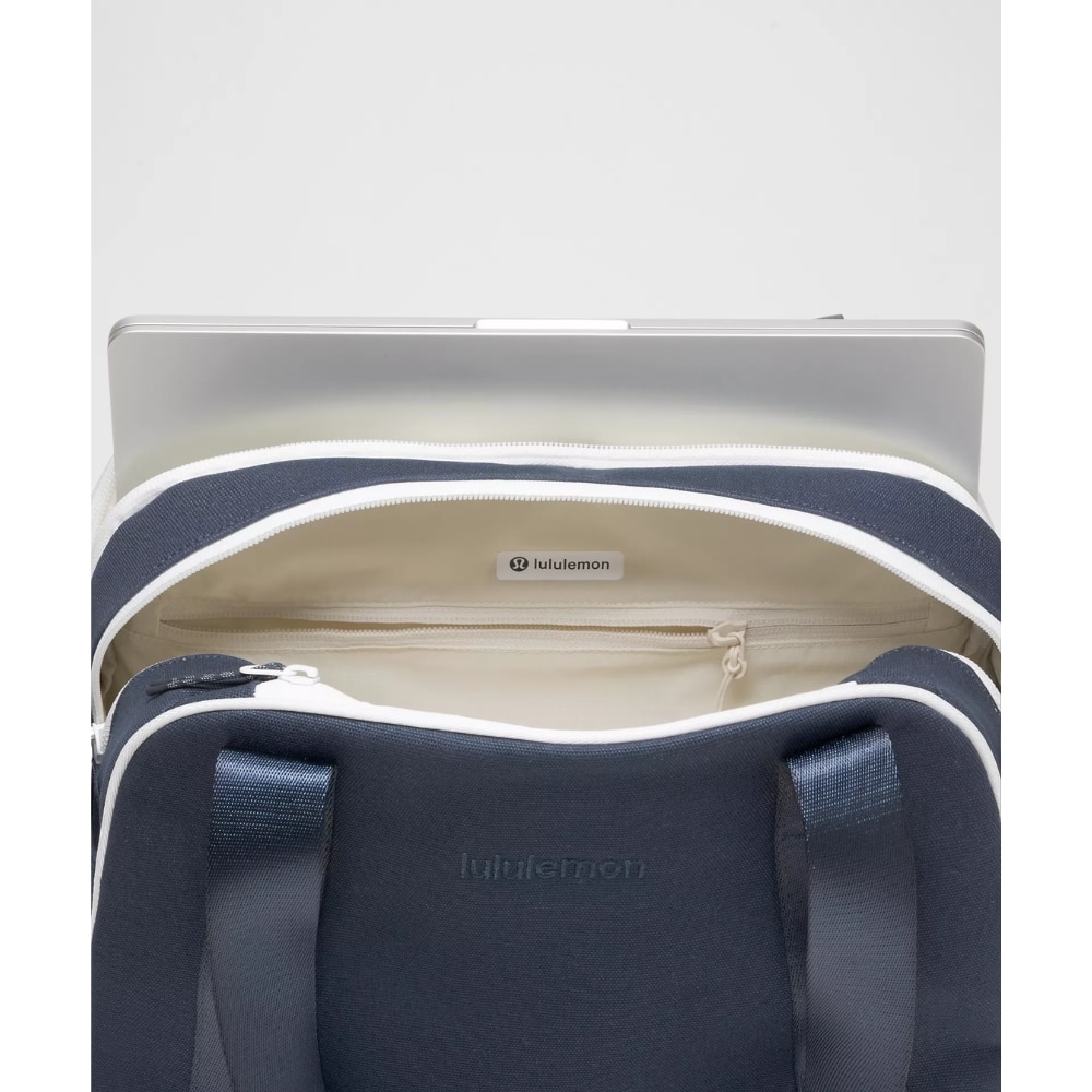 Navy Lululemon bag with a silver laptop protruding from the open main compartment.
