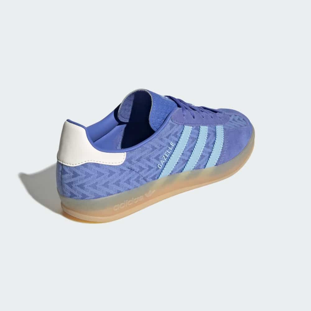 Blue Adidas Gazelle sneaker with light blue stripes and tan sole viewed from the side, showcasing the back heel tab.
