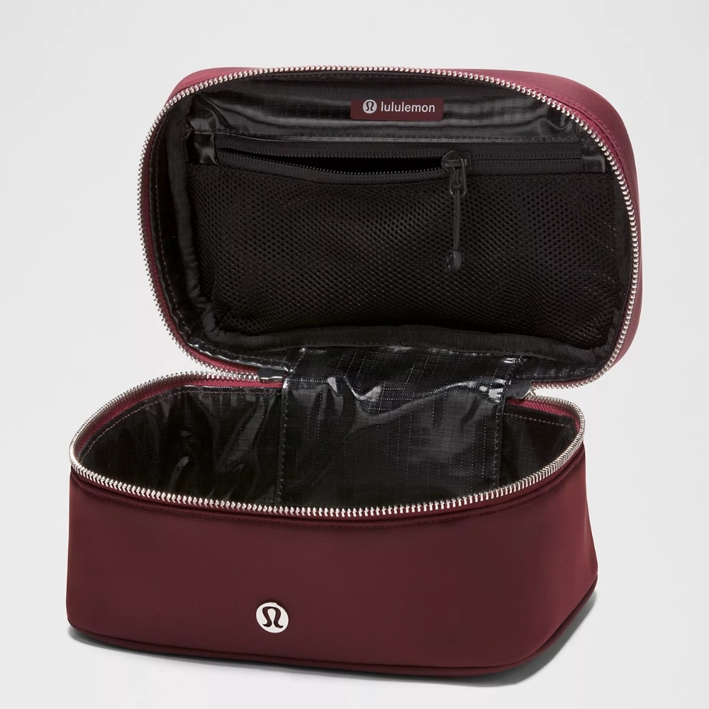 Burgundy Lululemon cosmetic bag opened to reveal a black mesh inner pocket and spacious main compartment with a zipper closure.