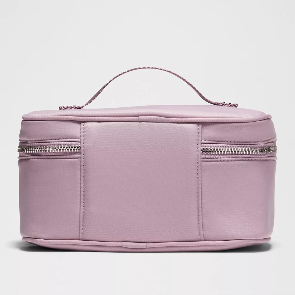 Light pink rectangular makeup bag with two side zippers and a small top handle on white background.