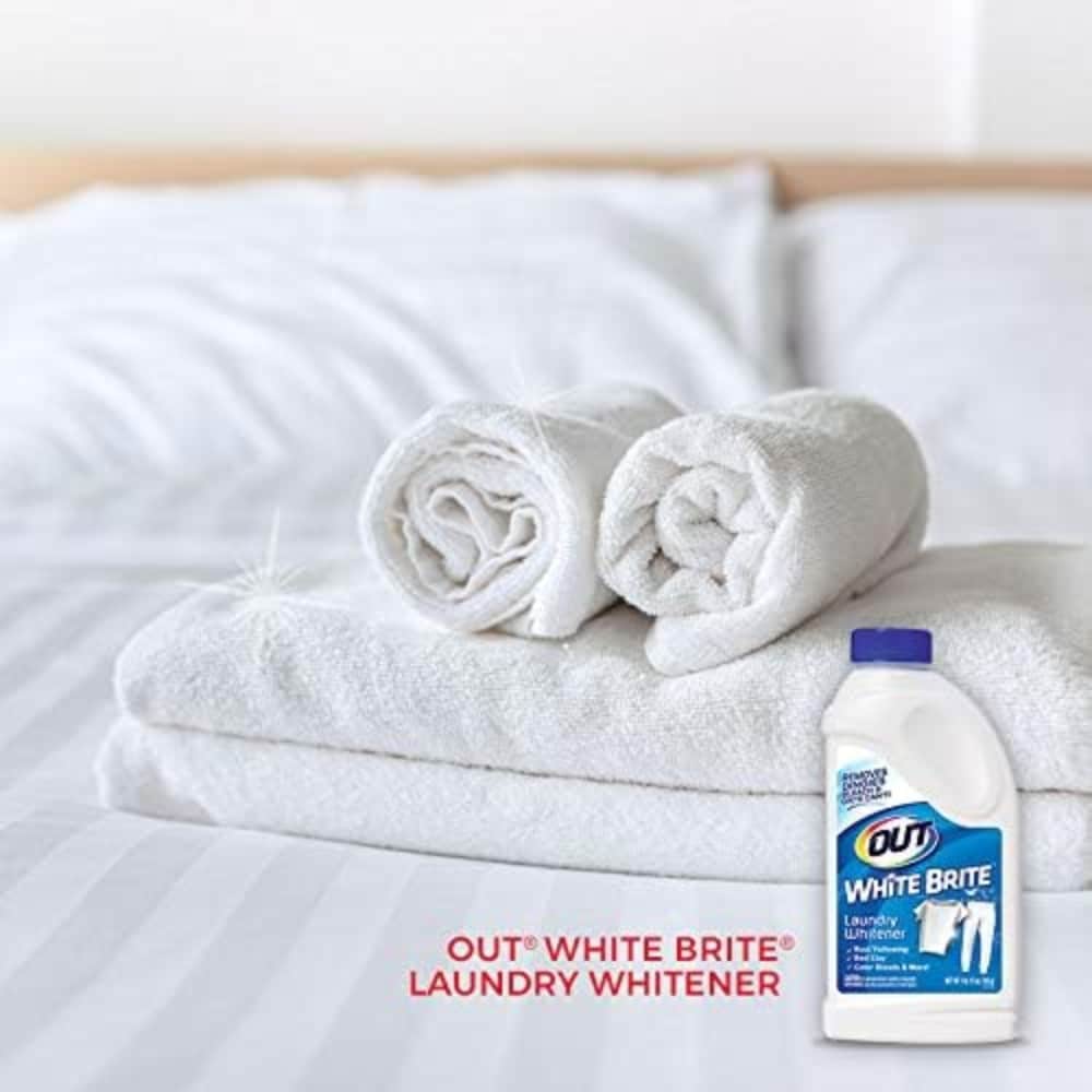 Laundry setup with white towels and a bottle of Out White Brite Laundry Whitener on a bed, promoting stain whitening.