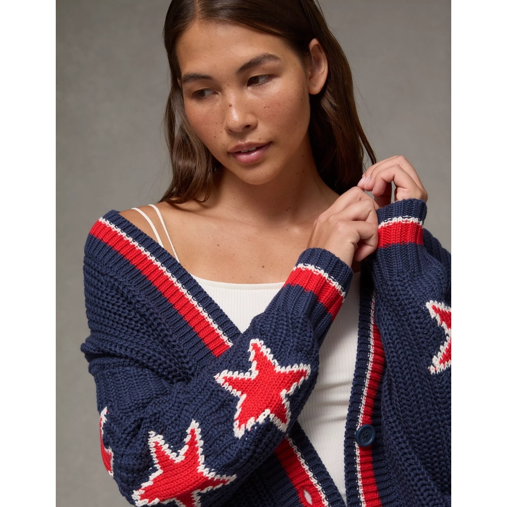Young woman wearing a navy cardigan with red stars, adjusting the sleeves on her shoulders.