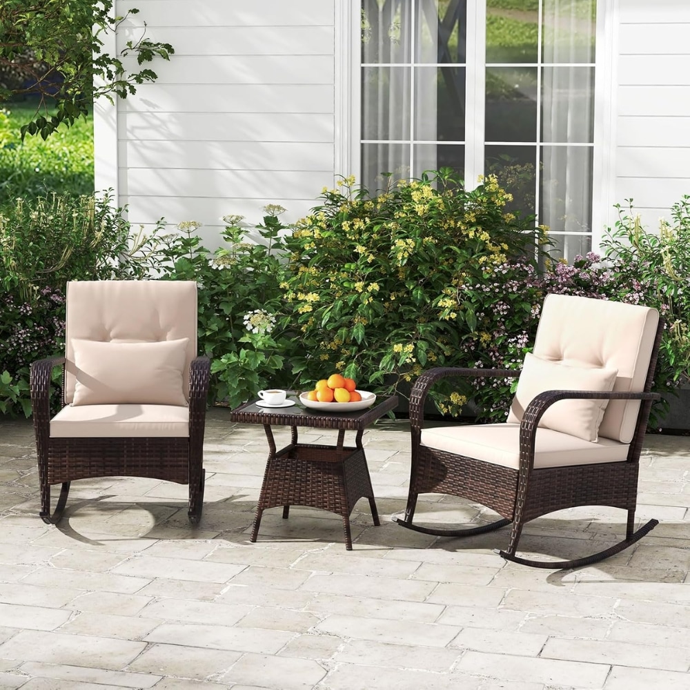 Two cushioned wicker lounge chairs with a small table between them on a stone patio, fruit bowl and cup on the table.