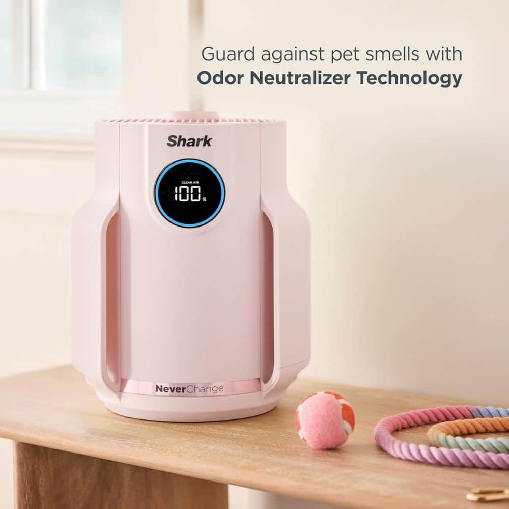 Pink Shark odor neutralizer device on a wooden table with a pink ball and a multicolored coil toy nearby.