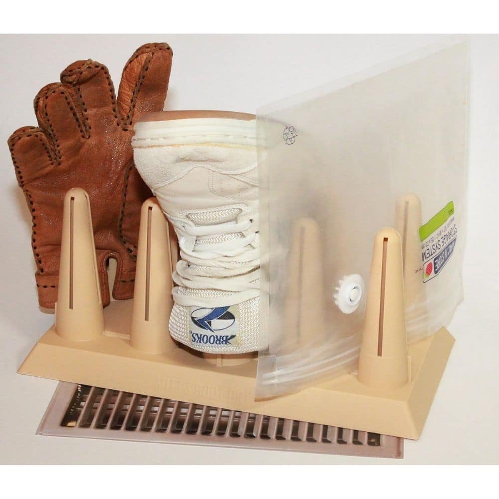Glove drying rack holding a brown leather glove and a white athletic glove, protected by a clear plastic panel on a beige base.