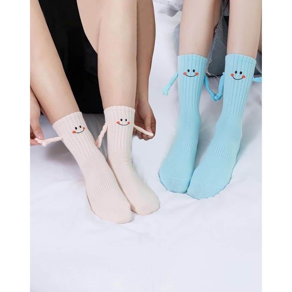 Two people sit on a bed wearing pastel socks with smiley-face cuffs: cream pink on the left and light blue on the right.