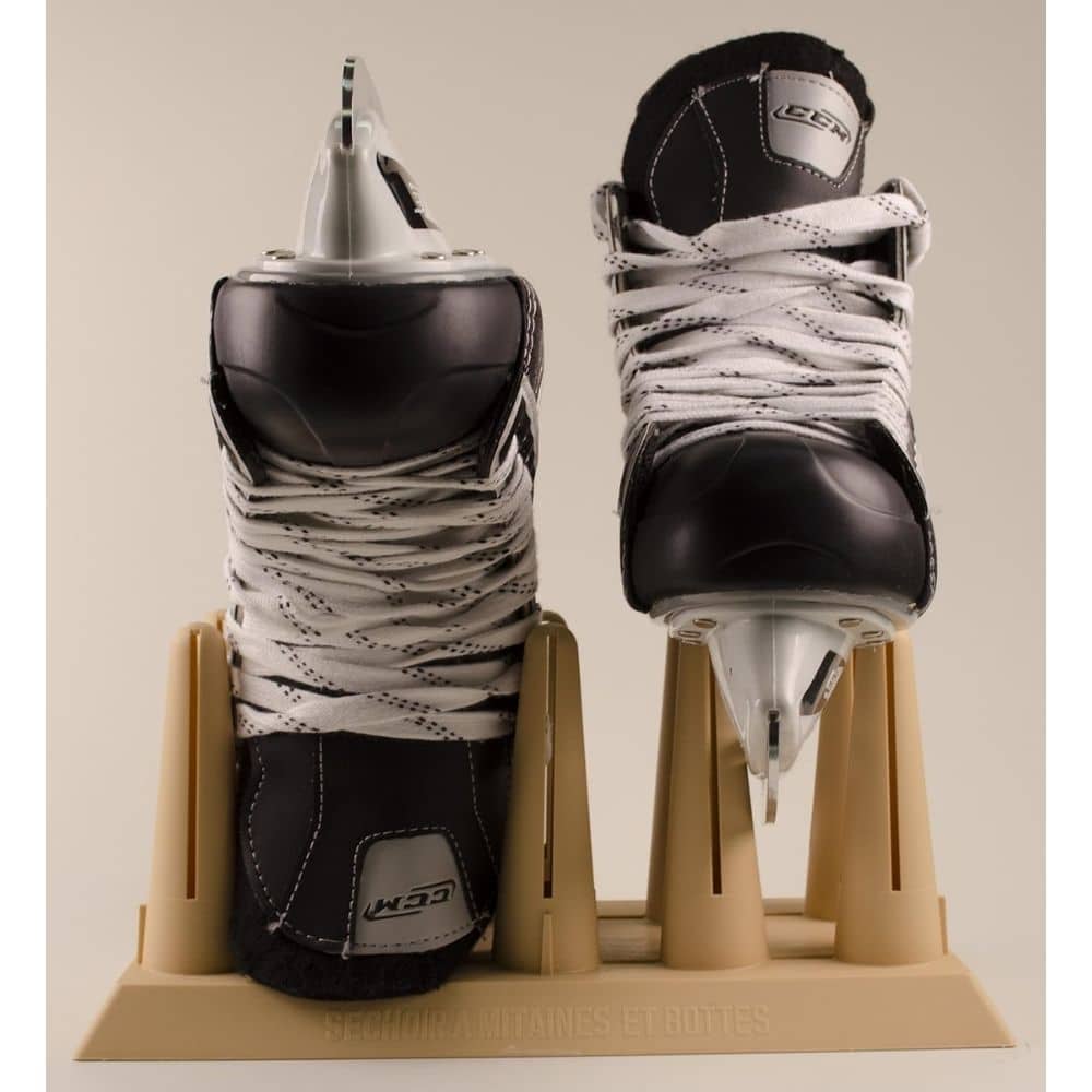 Two black-and-white ice hockey skates with white laces displayed on a tan display stand.