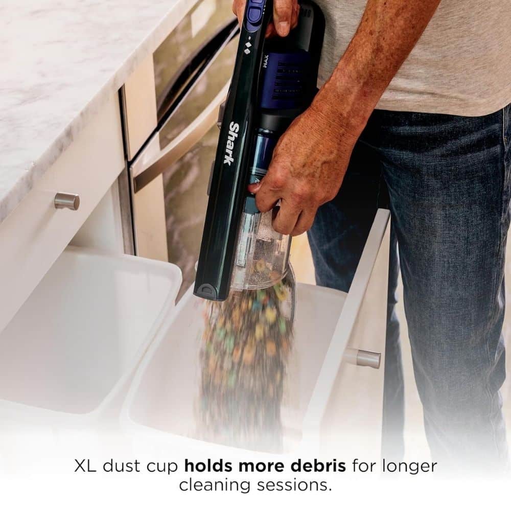 Close-up of a person using a Shark handheld vacuum, showing the clear dust cup releasing debris, highlighting the XL dust cup for longer cleaning sessions.