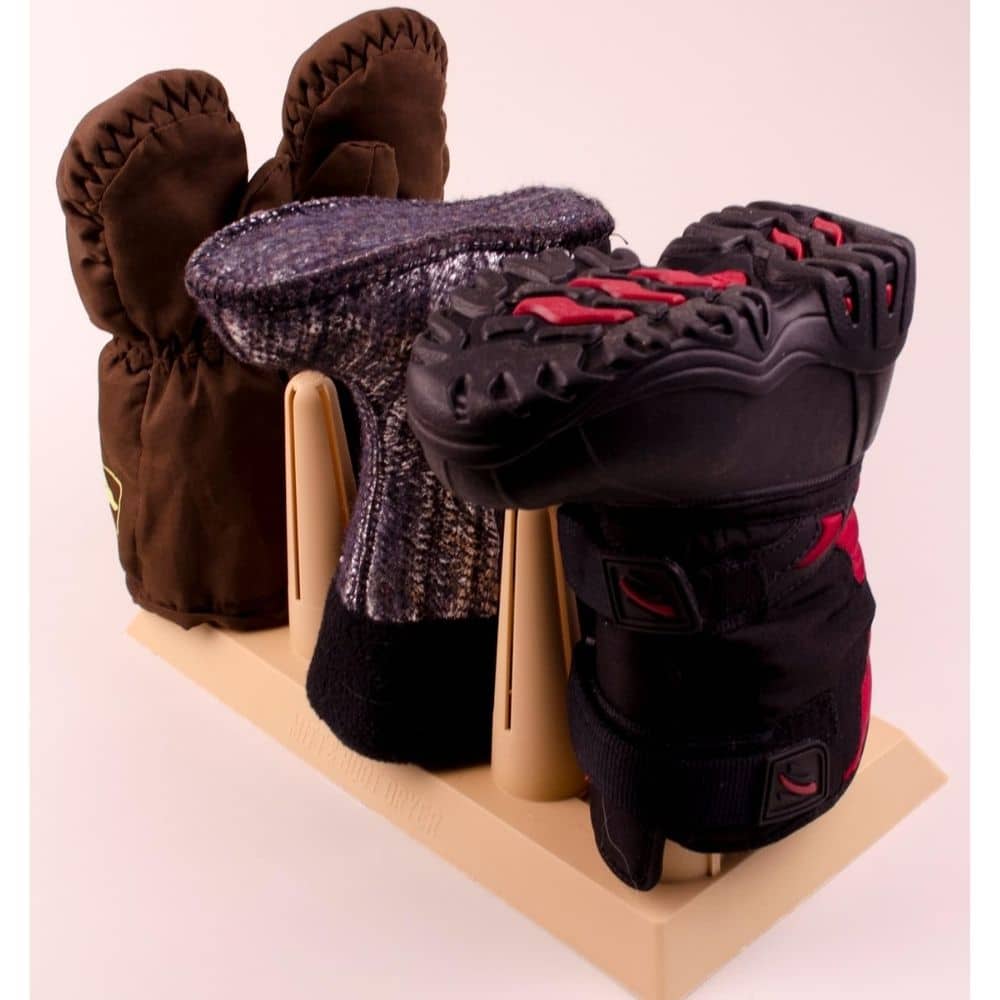 Assorted winter gloves and mittens arranged on a beige display rack against a pale pink background.