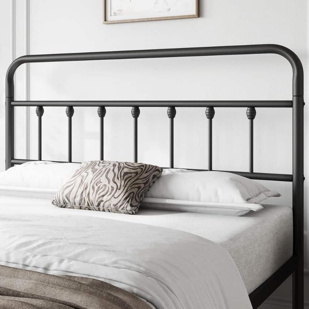 Metal bed frame with a dark finish and rounded top rail, white sheets, and a zebra-pattern throw pillow on a neatly made bed in a bright bedroom