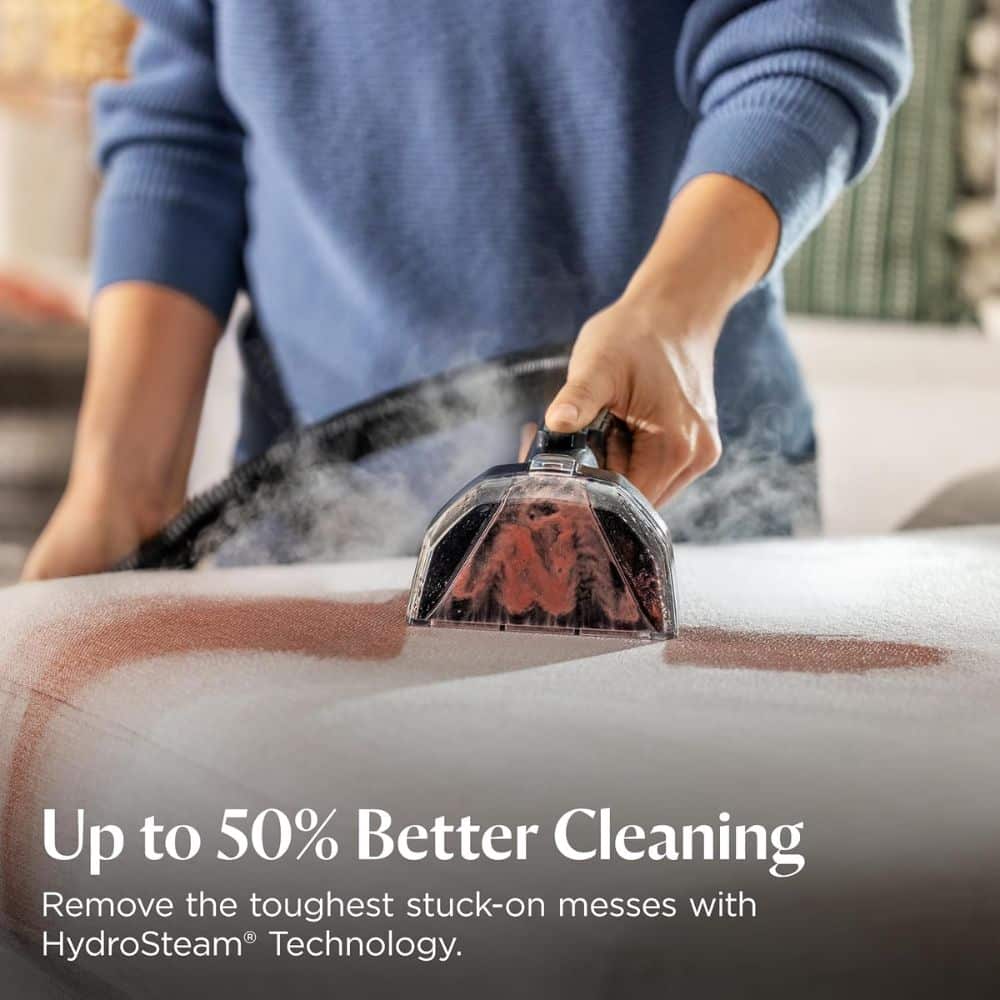 Hand holding a steam cleaning tool over a car surface with steam rising; promotional text reads 'Up to 50% Better Cleaning' and 'Remove the toughest stuck-on messes with HydroSteam Technology'