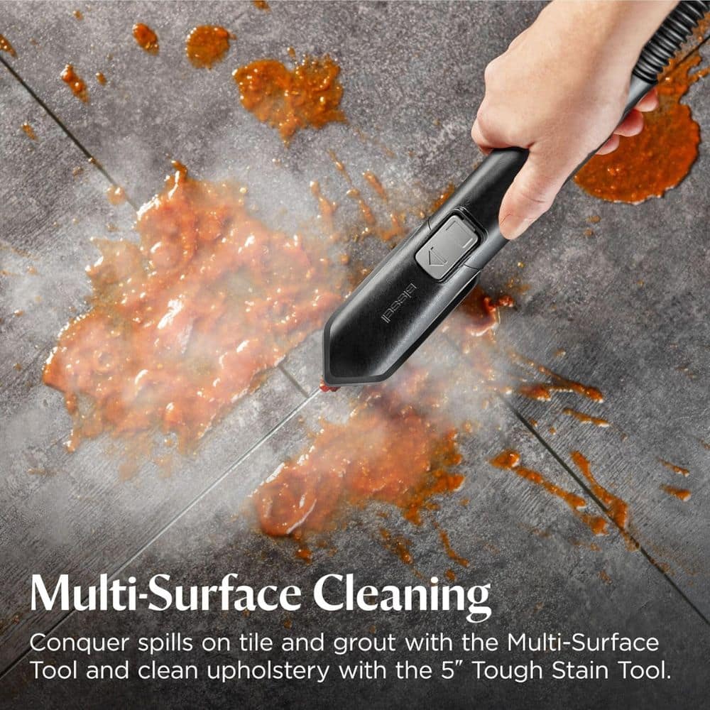 Hand holding a black multi-surface cleaning tool spraying an orange stain on gray tile; caption reads 'Multi-Surface Cleaning'.